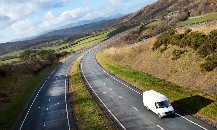 Lone white van courier service on a rural dual carriageway